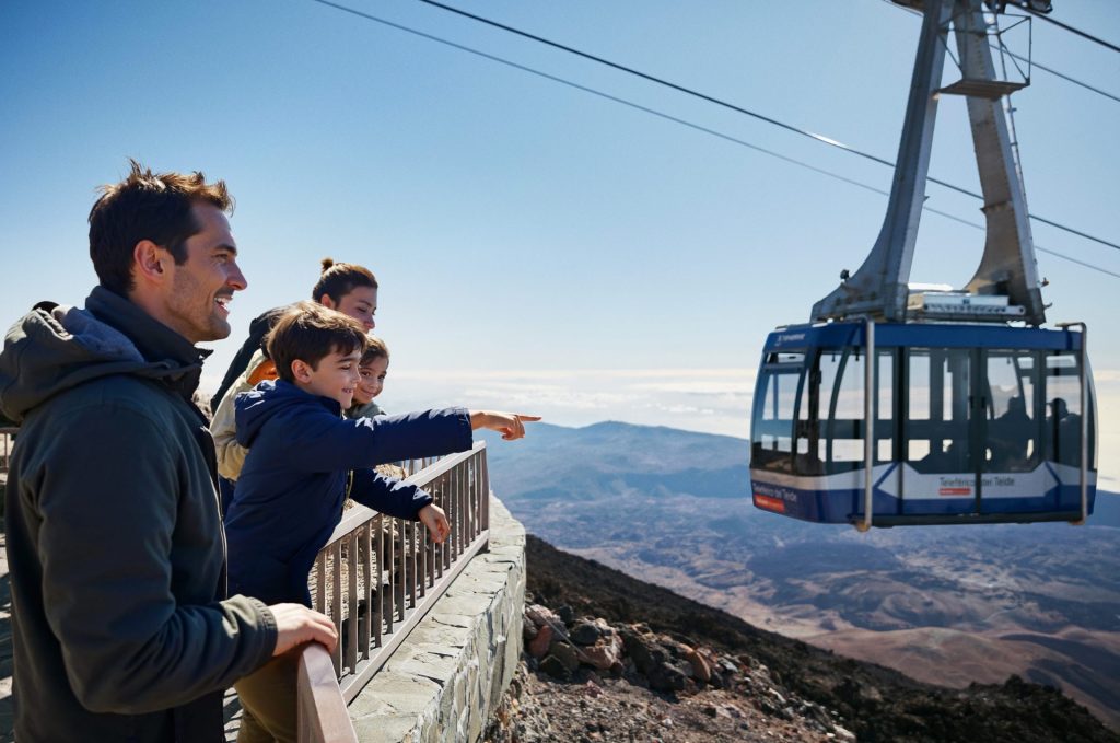 Una familia en un teleférico observa las montañas desde lo alto, disfrutando de la vista panorámica.
