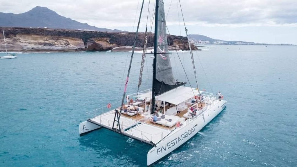 Catamarán navegando en el océano con personas a bordo disfrutando del paisaje marino.