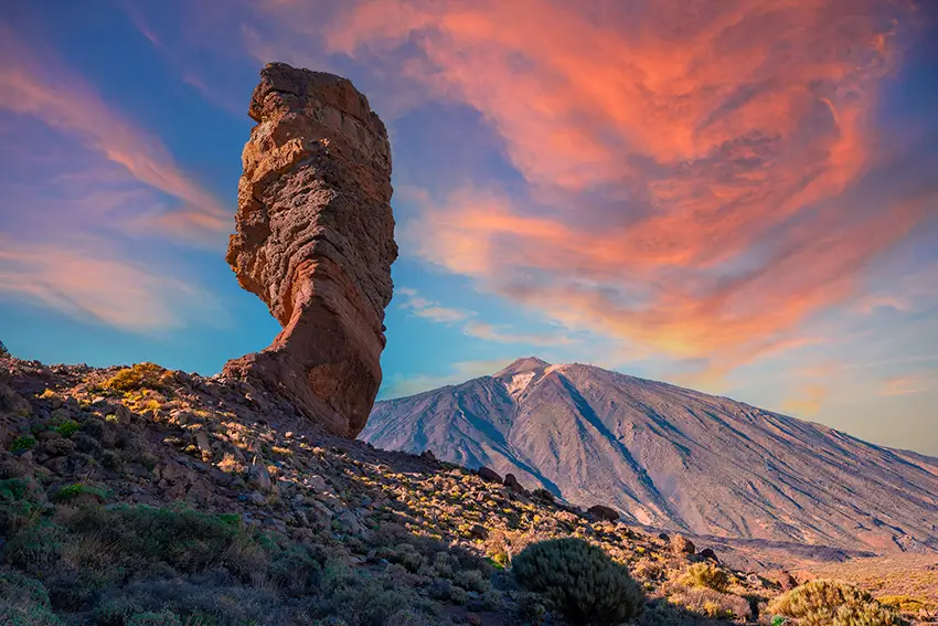 Formación rocosa al atardecer en las montañas, con tonos cálidos iluminando el paisaje natural.