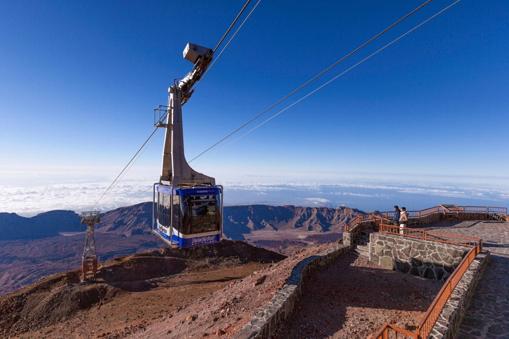 Teleférico subiendo hacia la cima de una montaña, rodeado de un paisaje natural impresionante.